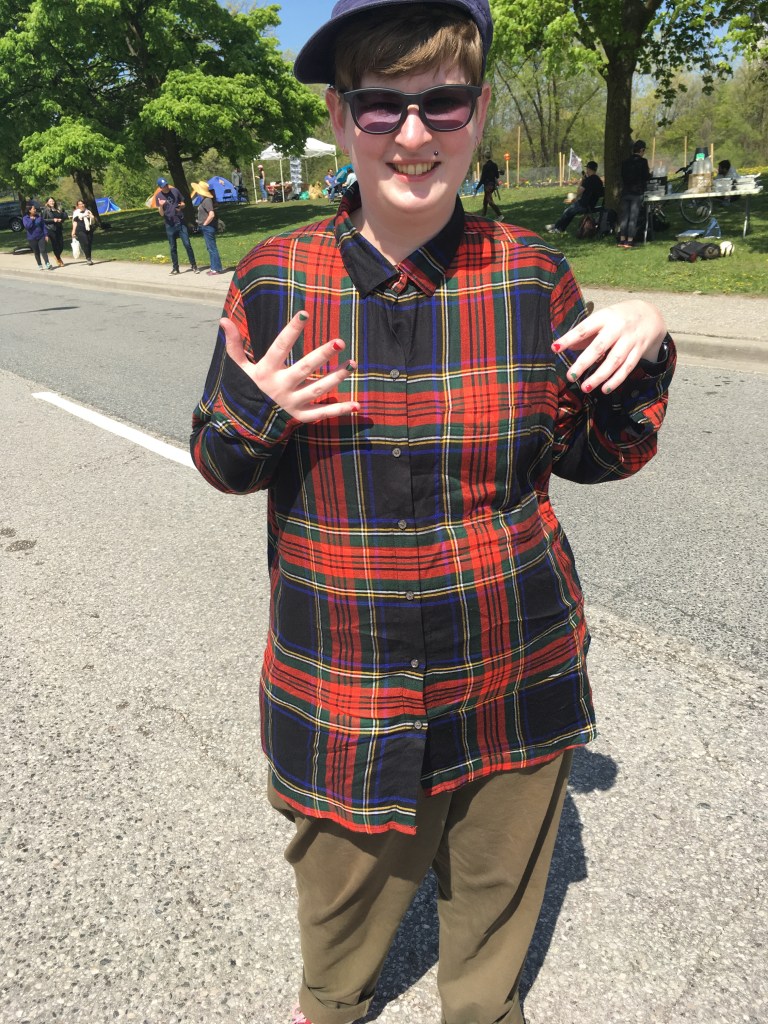 Image Description: My epic strike fashion of a hat, sunglasses, plaid shirt and khaki pants and for some reason Christmas themed painted nails
